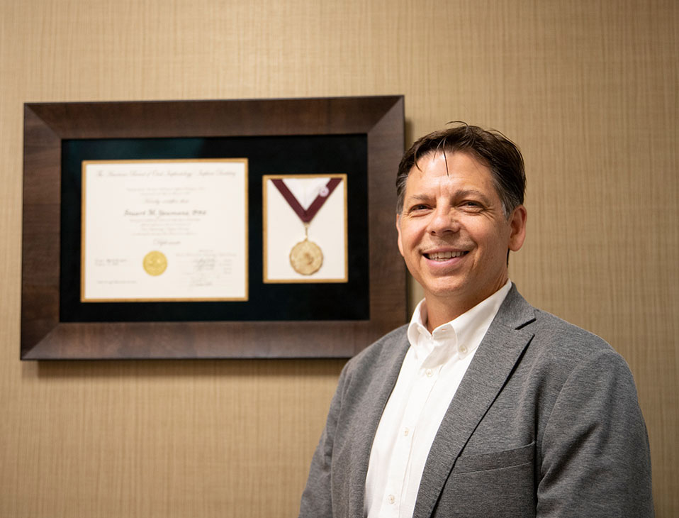 Dr. Stuart Youmans beside his framed American Board of Oral Implantology/Implant Dentistry Diplomate certificate and medal