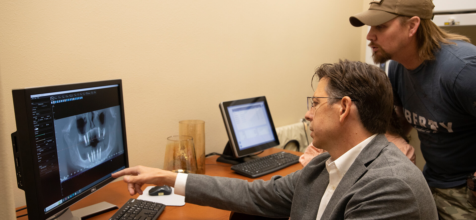 Dr. Youmans reviewing a panoramic x-ray on screen with an implant patient